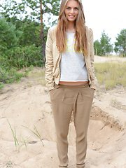 Delicious teen beauty undressing and spreading her long shapely legs outdoors on the sand.